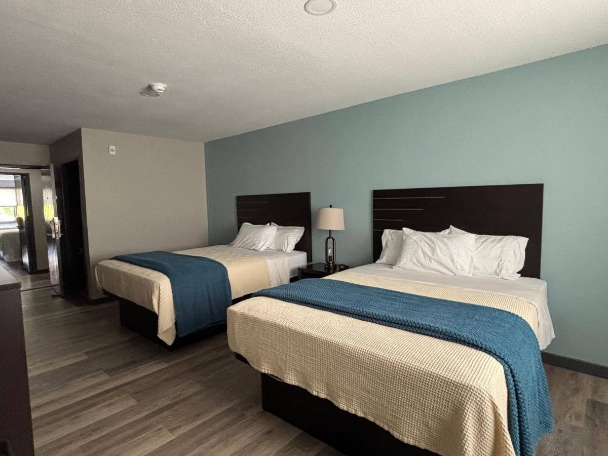 Double queen room with teal accent wall and wood floors